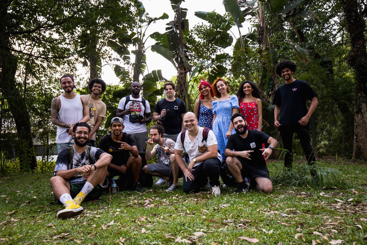 Home A diverse group posing happily together in a lush, outdoor setting.