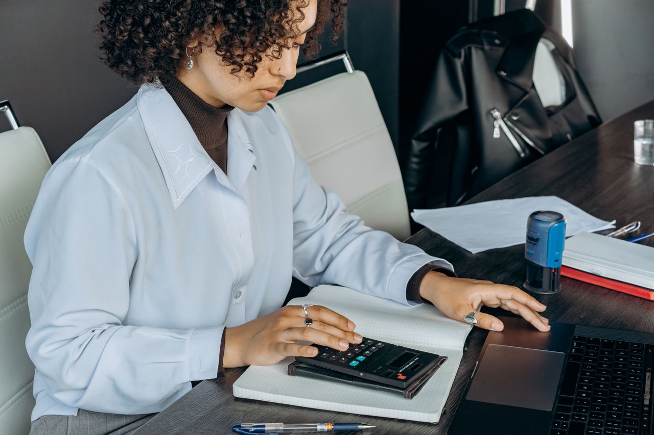 Home Young woman in office using a calculator for financial calculations.